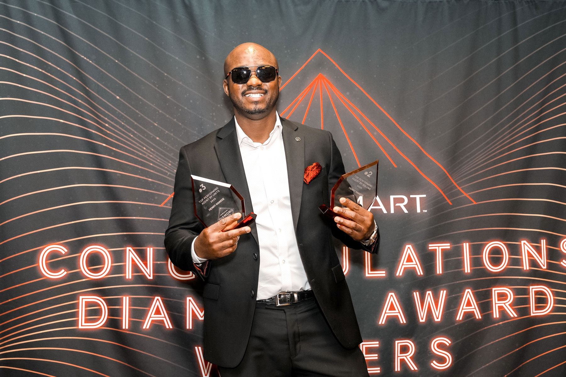 Henry holding his two 2025 top performing agent trophies