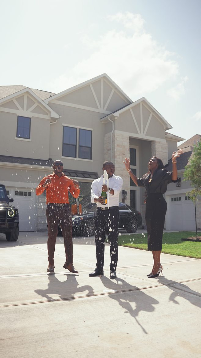 Henry celebrating with his clients as champagne sprays on the driveway